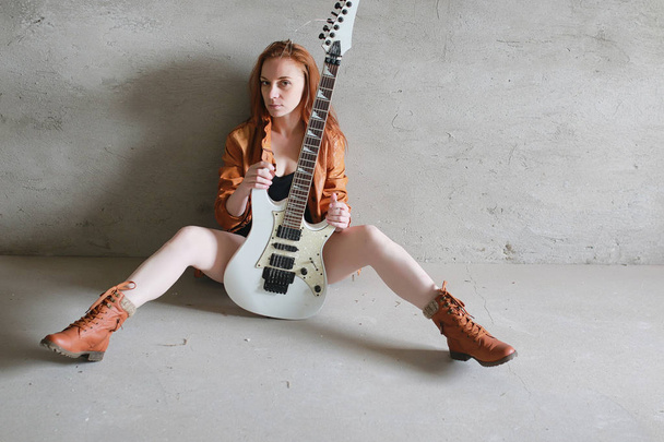 Young red-haired girl with an electric guitar. Rock musician gir - Photo, Image
