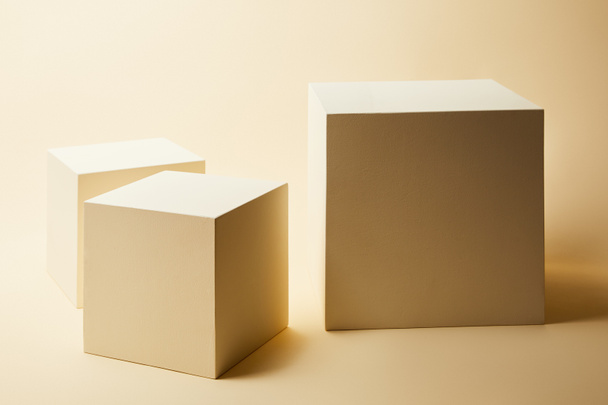 bodegón de cubos en diferentes tamaños sobre superficie beige
 - Foto, imagen