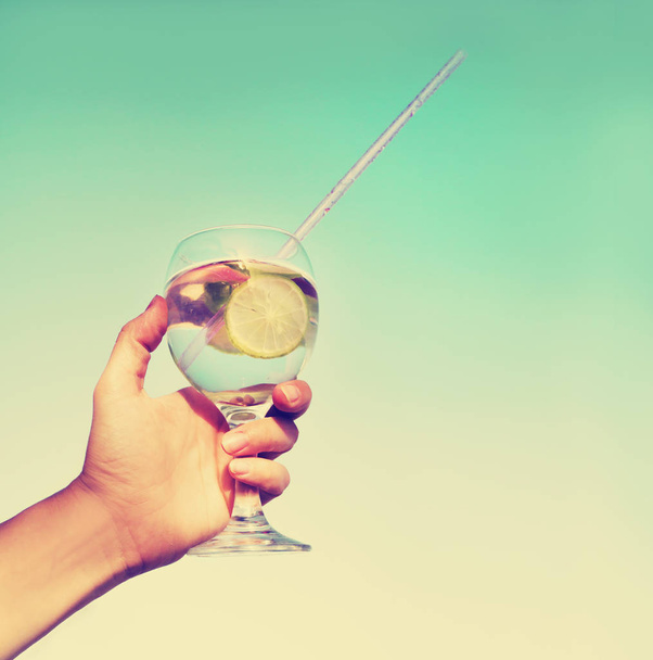 cropped image of hand holding lemonade in glass with straw - Zdjęcie, obraz