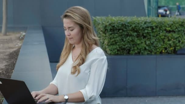 Young businesswoman working on laptop in city park business center - Video, Çekim