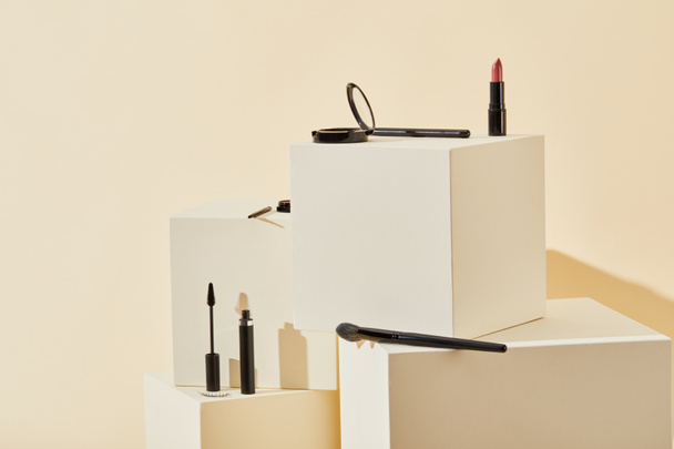 various makeup supplies lying on beige cubes - Fotó, kép