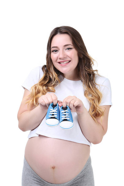 Pregnant woman holding baby shoes on white background - Фото, зображення