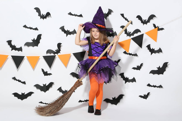Young girl in halloween costume with broom on white background - 写真・画像