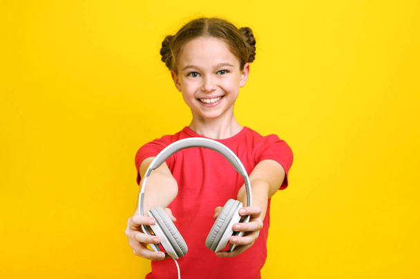 Young girl with headphones on yellow background - 写真・画像
