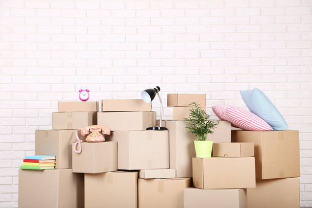 Cardboard boxes with household stuff on brick wall background - Φωτογραφία, εικόνα