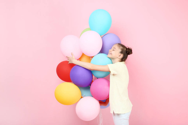 Cute young girl with colored balloons on pink background - 写真・画像