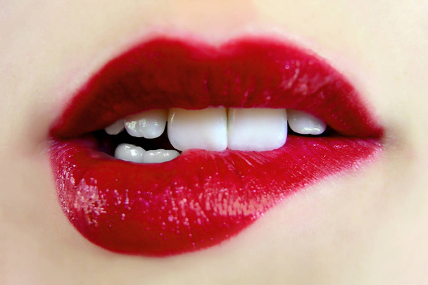 Γυναίκα προκλητικό στιλπνότητα κόκκινα χείλη. Άνοιξε το αισθησιακό στόμα της γυναίκας με τα δόντια να δαγκώνει τα χείλη της. Υγεία και ομορφιά έννοια που αφορούν καλλυντικά και θηλυκό επιχειρήσεων μόδας - Φωτογραφία, εικόνα