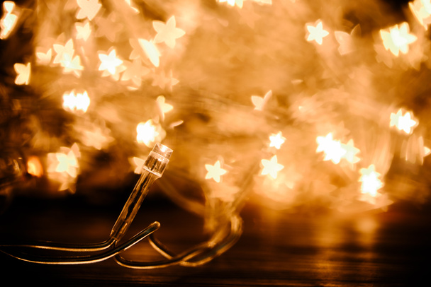 close up view of festive garland and stars bokeh lights backdrop - Zdjęcie, obraz