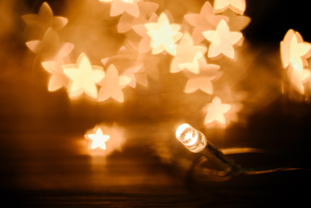 close up view of festive garland and stars bokeh lights backdrop - Foto, Imagem