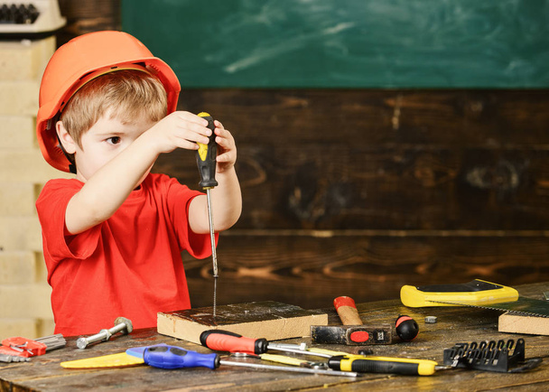 Small kid holding a screwdriver with both hands. Little boy discovered a new toy. Early learning concept - Φωτογραφία, εικόνα