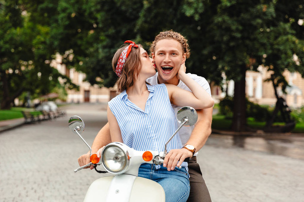 Portrait of a lovely young couple riding on a motorbike together at the city street - Fotó, kép