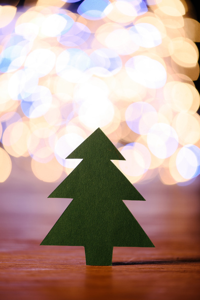 close up view of green paper christmas tree on wooden tabletop and bokeh lights background - Fotoğraf, Görsel
