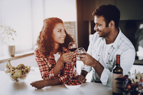 Afro American Couple Drinking Wine On In Kitchen. Weekend Concept. Family Holiday Resting. Romantic Date. Cheerful Sweethearts. Glass Of Wine. Happy Together. Looking At Each Other. - Фото, зображення