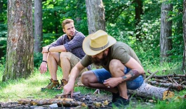 Camping in forest. How to build bonfire outdoors. Men on vacation. Man brutal bearded hipster prepares bonfire in forest. Arrange the woods twigs or wood sticks. Ultimate guide to bonfires - Valokuva, kuva