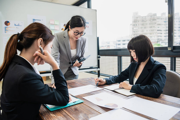 Young businesswoman giving some new ideas about project to her colleagues in conference room. Business people discussing over new business project in office. - 写真・画像