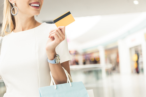 plan recadré d'une jeune femme souriante tenant une carte de crédit dans un centre commercial
 - Photo, image