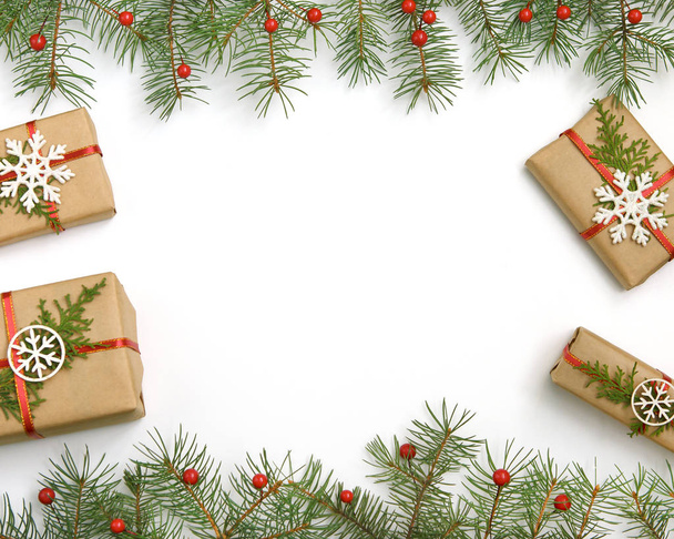 Karácsonyi ajándék dobozok díszített papír kézműves és a fehér hópelyhek a piros háttér felülnézet. Boldog karácsonyt üdvözlőlap. - Fotó, kép