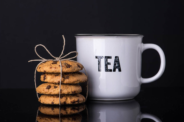 Breton gift biscuits and a cup of tea on a black background with steam. - Zdjęcie, obraz