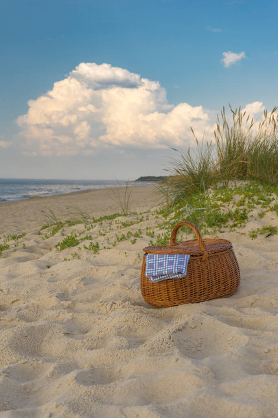 Piknik kosár a festői strand és a felhők ellen, hétvégi szünet koncepció - Fotó, kép