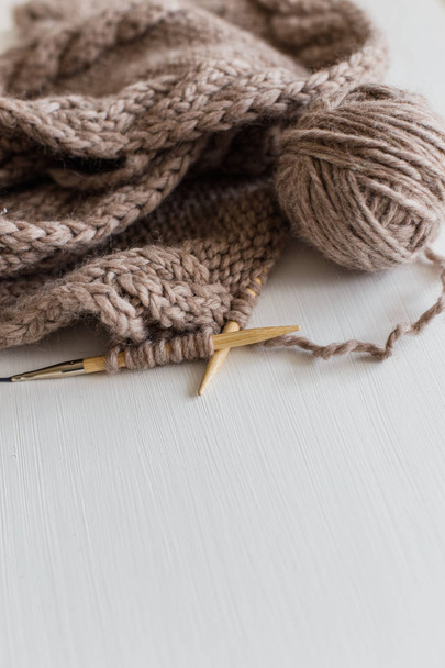 Beige knitting wool and knitting needles on white wooden background. Knitting as a hobby. Accessories for knitting. - Photo, image