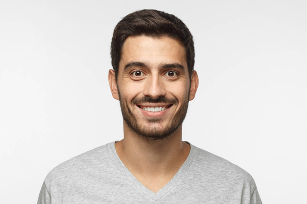 Close up portrait of young smiling handsome guy in gray t-shirt isolated on gray background - Foto, immagini