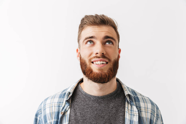 Portrait of a smiling young bearded man looking up isolated over white - Φωτογραφία, εικόνα
