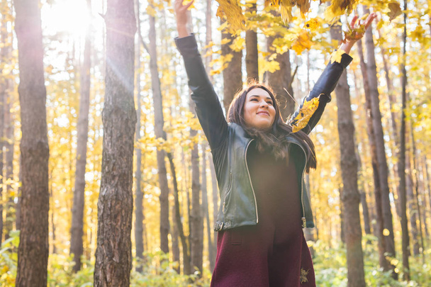 Joven mujer divertida lanzando hojas en el parque de otoño
 - Foto, Imagen