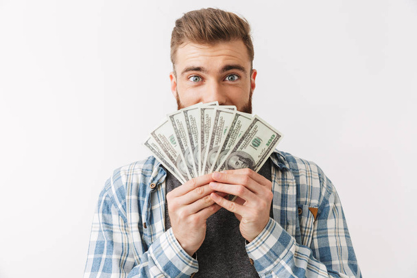 Portrait of a satisfied young bearded man standing isolated over white, showing money banknotes - Foto, Bild