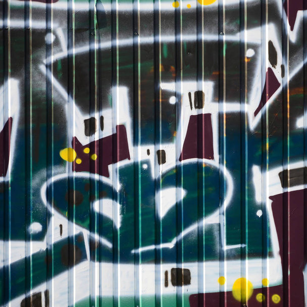 Фрагмент граффити рисунков. Старая стена декорирована краской в стиле уличного искусства. Цветная текстура фона в зеленых тонах
. - Фото, изображение