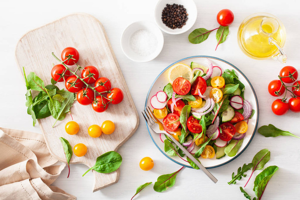 здоровый цветной веганский салат из помидоров с огурцом, редиской, луком
 - Фото, изображение