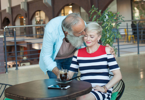 Happy beautiful older couple drink coffee together - Fotó, kép