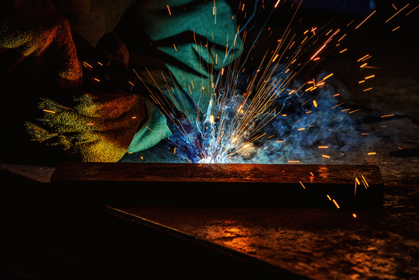 image recadrée d'ouvrier de fabrication soudant le métal avec des étincelles à l'usine
  - Photo, image