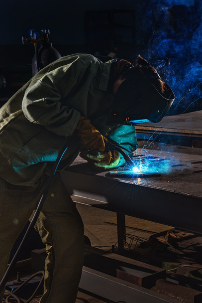 male manufacture worker welding metal with sparks at factory  - Photo, Image