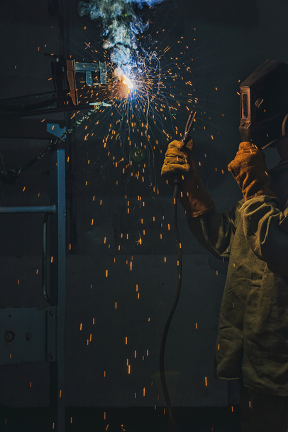 selective focus of welder in protection mask working with metal at factory  - Photo, Image