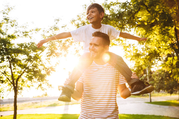 Image of happy young man father having fun with his son outdoors in park. - Fotoğraf, Görsel