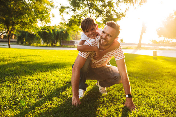 Happy father spending time with his little son at the park, playing on a grass - Photo, image