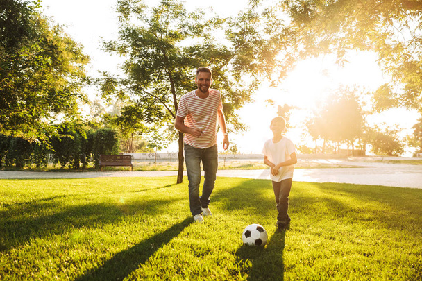 Gülümseyen baba oğluyla bir çim futbol oynarken küçük parkta, vakit - Fotoğraf, Görsel