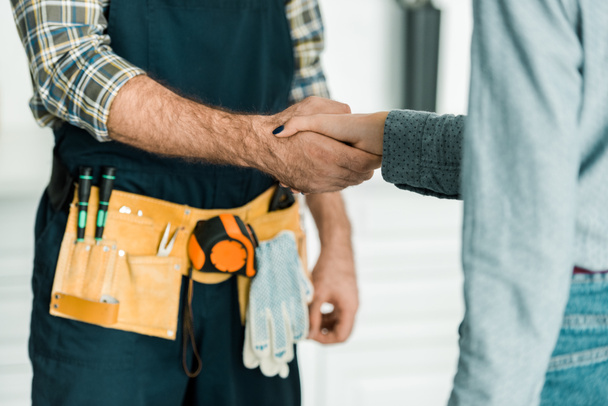 cropped image of plumber and customer shaking hands in kitchen - Φωτογραφία, εικόνα