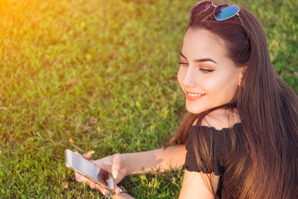 junges Teenagermädchen textet auf Handy draußen - Foto, Bild