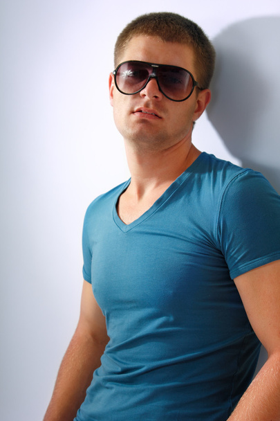 adam genç yakışıklı sporcu ile güneş gözlüğü ve mavi t-shirt isol - Fotoğraf, Görsel