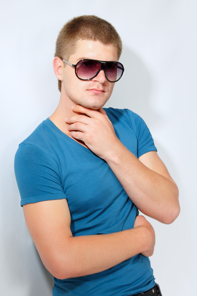 adam genç yakışıklı sporcu ile güneş gözlüğü ve mavi t-shirt - Fotoğraf, Görsel
