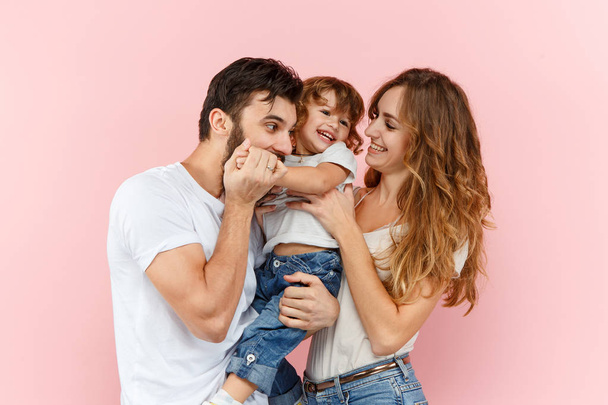 A happy family on pink studio background. The father, mother and son posing together - Fotoğraf, Görsel