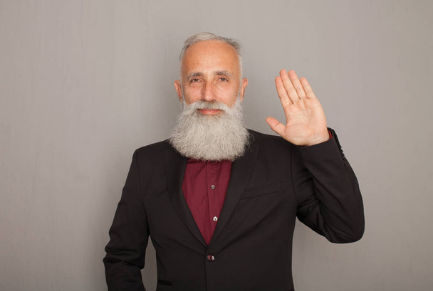 Hello! A happy middle aged bearded man shows his hand a greeting sign. - Photo, Image