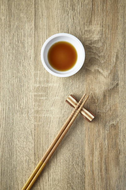 Палички для їжі і соєвого соусу на фоні дерев'яний стіл з копією простору. Дизайн, сонячне світло опівдні, японському стилі. - Фото, зображення