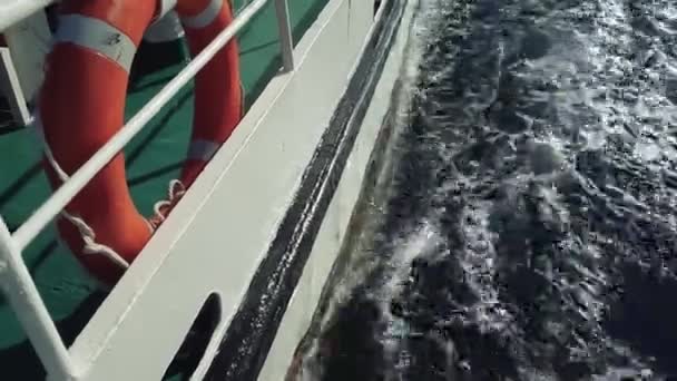 Statek z koło ratunkowe na pokładzie przenosi na morzu fale. fale rozchodzą się z łodzi - Materiał filmowy, wideo