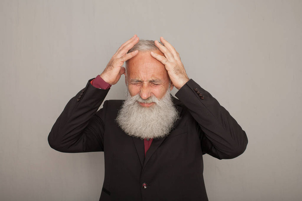 Old man holding his temples with opressive pain.Senior business man with headache. - Foto, imagen