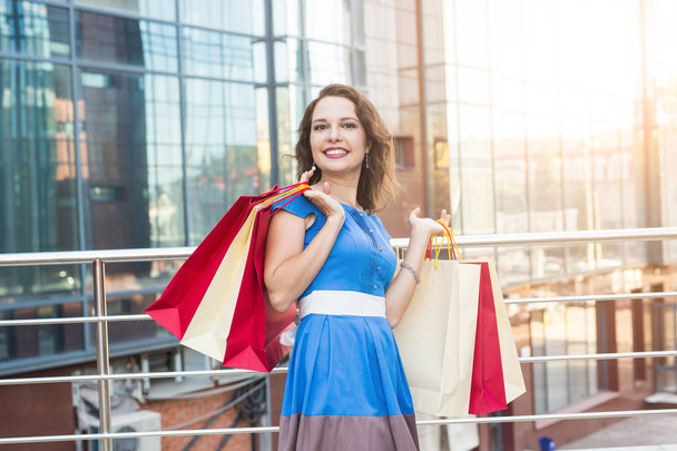 Purchase, sale and people concept - young happy smiling woman with shopping bags - 写真・画像