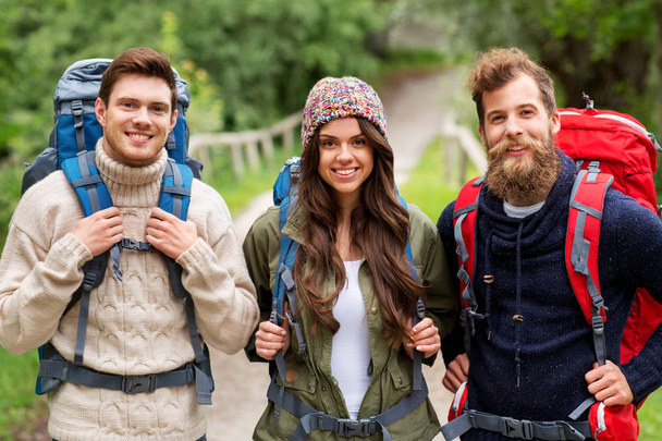 glückliche Freunde oder Reisende mit Rucksack beim Wandern - Foto, Bild