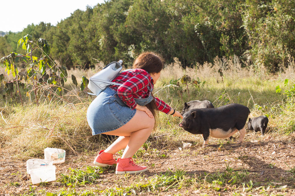 Mutlu genç kadın küçük yaban domuzları doğa üzerinde çalış. - Fotoğraf, Görsel