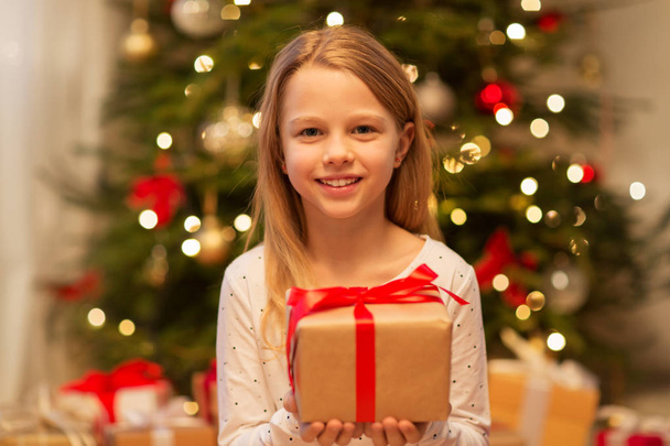 smiling girl with christmas gift at home - Fotó, kép